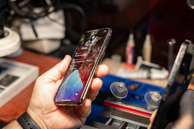 a hand holding a broken iphone